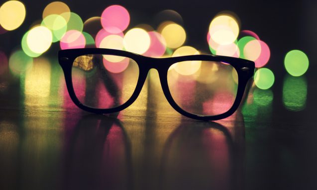 Black glasses laying on the floor with bright lights in the background