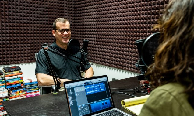Clay Conner recording a podcast with a woman inside a recording studio