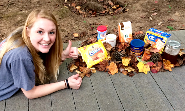 Woman laying on ground next to autumn themed food and leaves