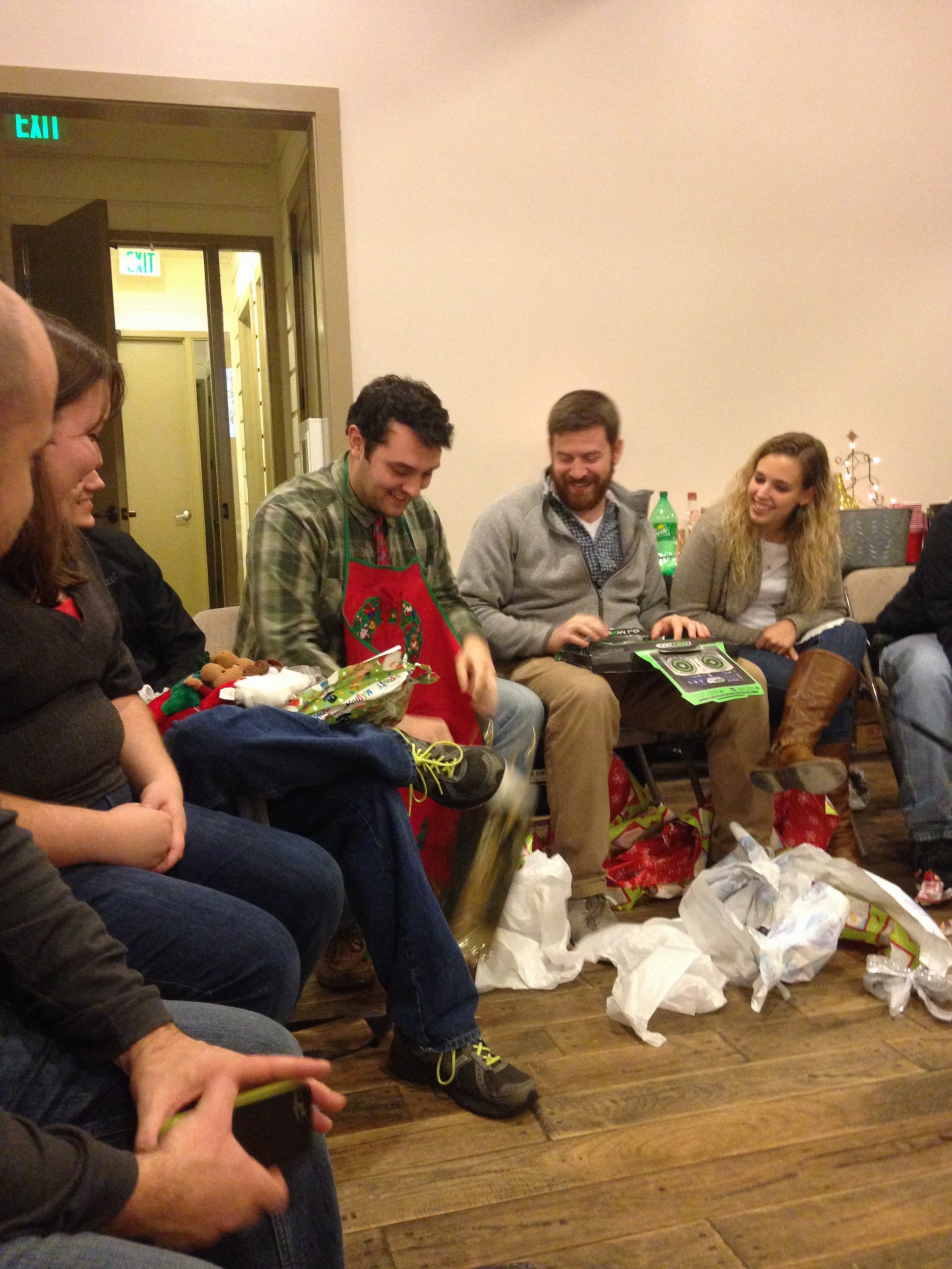 Multiple people sitting around opening Christmas gifts