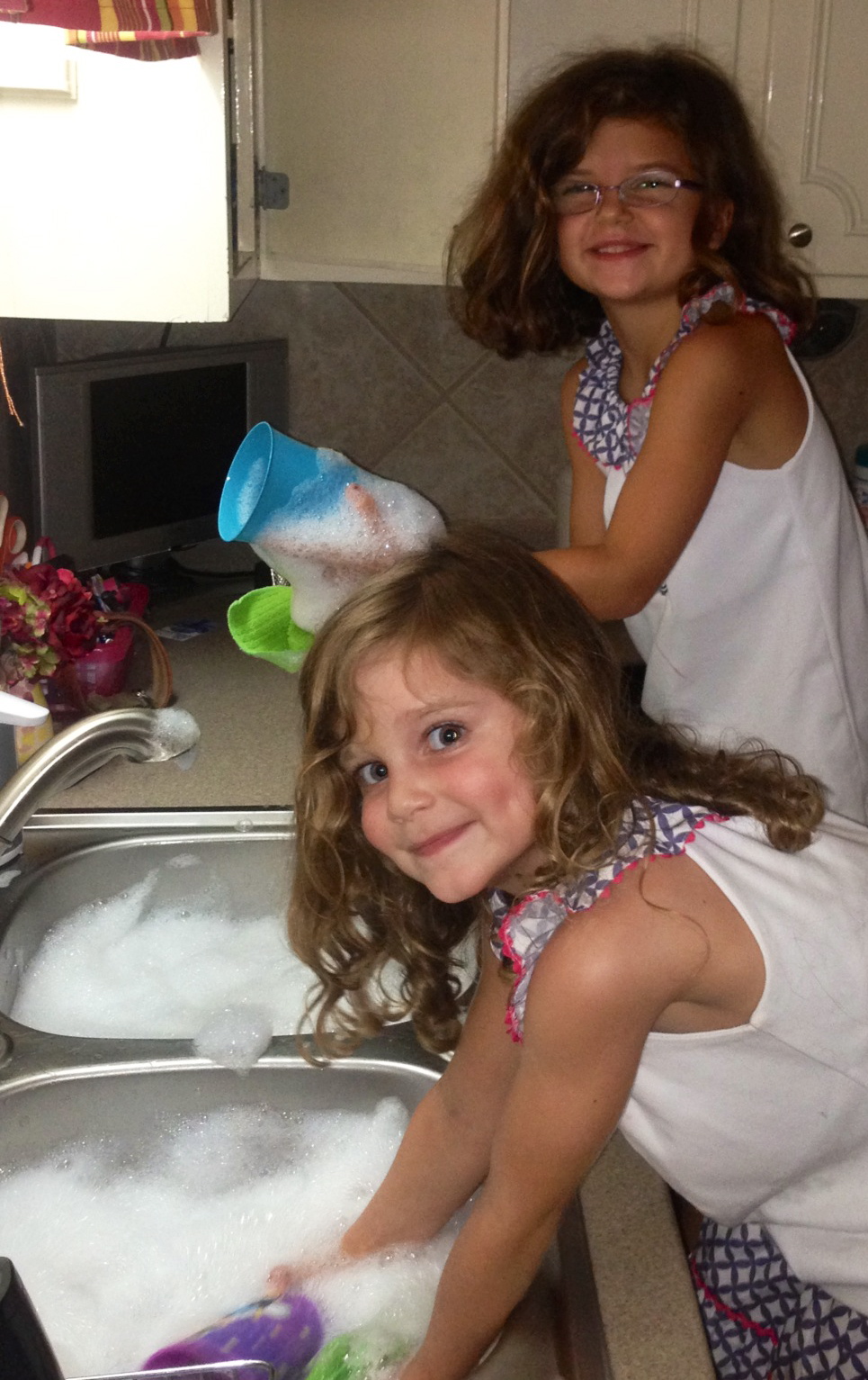 Two little kids washing dishes in the sink
