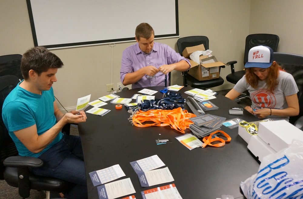 Infomedia emplyees sitting at a table putting together lanyards