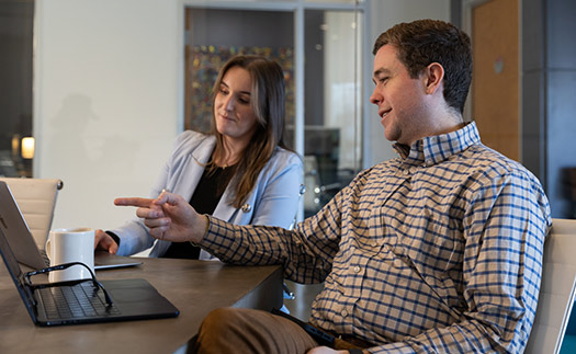 Woman and man sitting at table looking at laptop