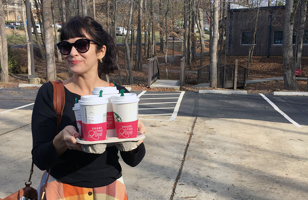 Carrie Rollwagen stands in the parking lot of Infomedia with four cups of Starbucks coffee to treat her coworkers