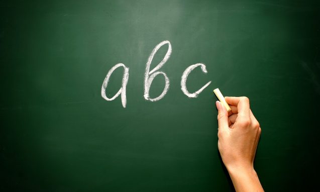 a woman's hand writing abc on a blackboard with chalk