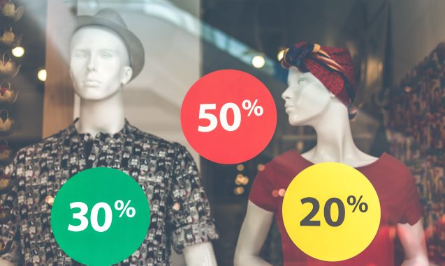 Mannequins in front of a window with stickers with discount percentages in front of them