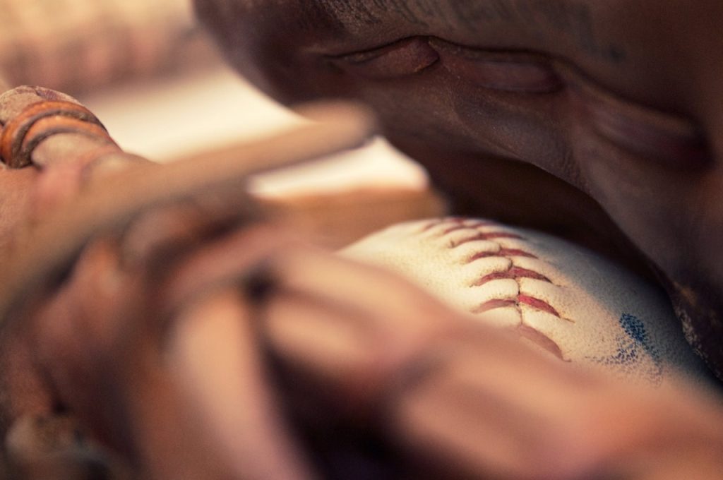 A close up picture of a baseball inside a baseball glove