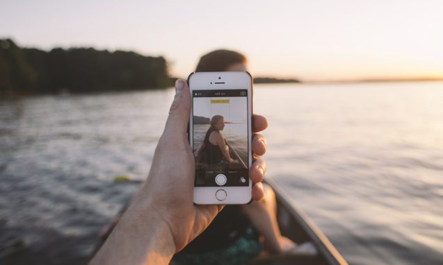 person takes picture of woman in canoe on a lake