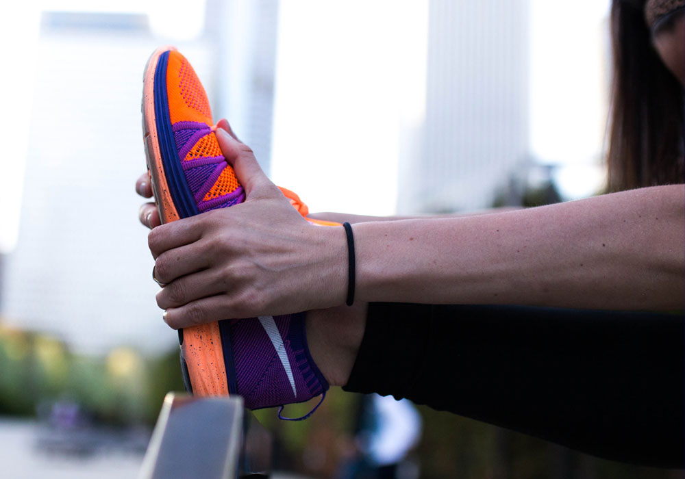 Runner extends a leg and grasps a purple and orange sneaker