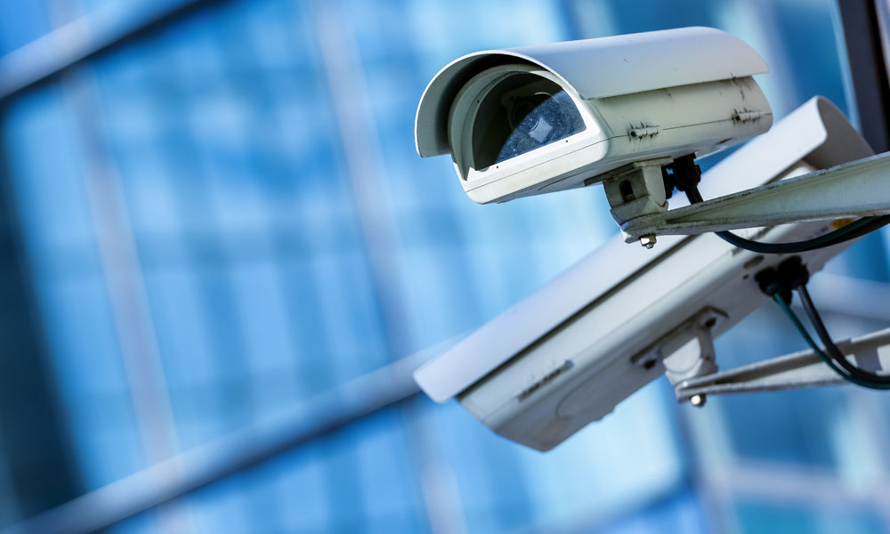 two street security cameras loom over downtown city area