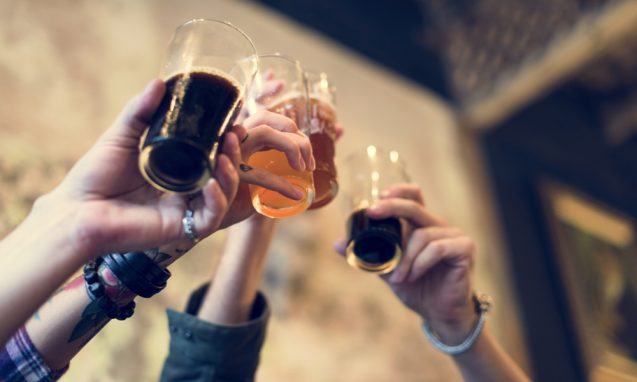 group of hands holding glasses of light and dark beer