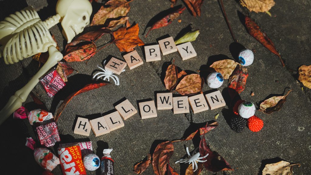 scrabble tiles spelling out "halloween" surrounded by candy