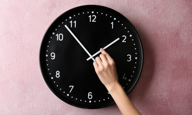 woman's hand moving the hands on a black clock