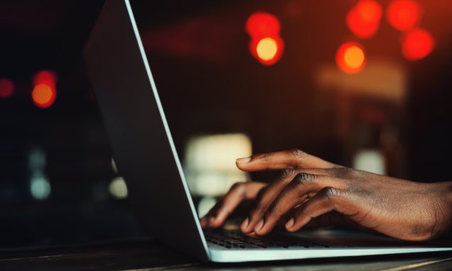 black man typing on a laptop keyboard
