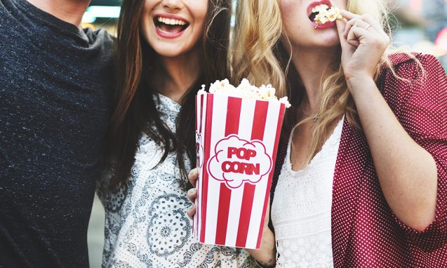 three young movie-goers share popcorn during a film festival