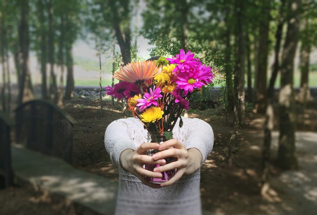 Woman holding a vase of flowers in the woods