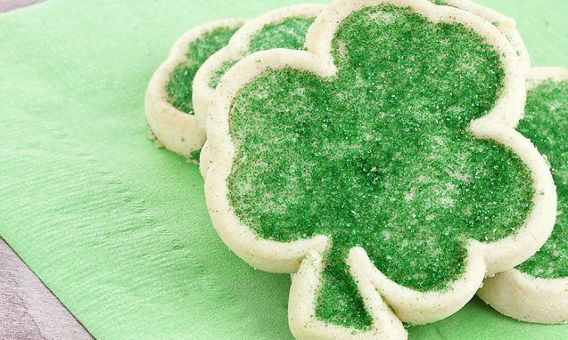 Four leaf clover-shaped sugar cookies decorated with green sugar crystals