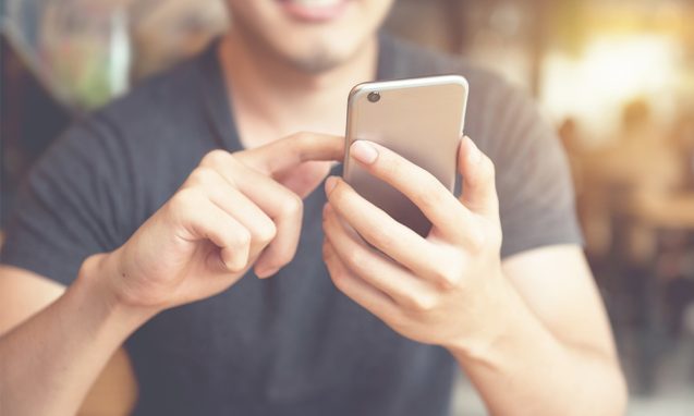 smiling man scrolls on mobile device