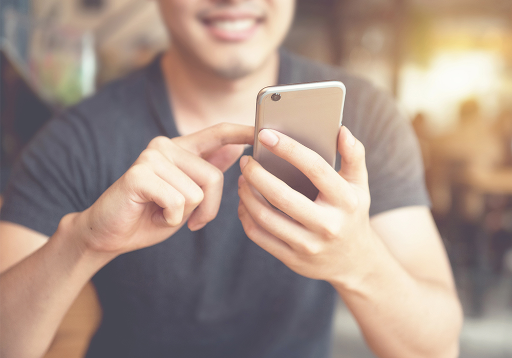 smiling man scrolls on mobile device