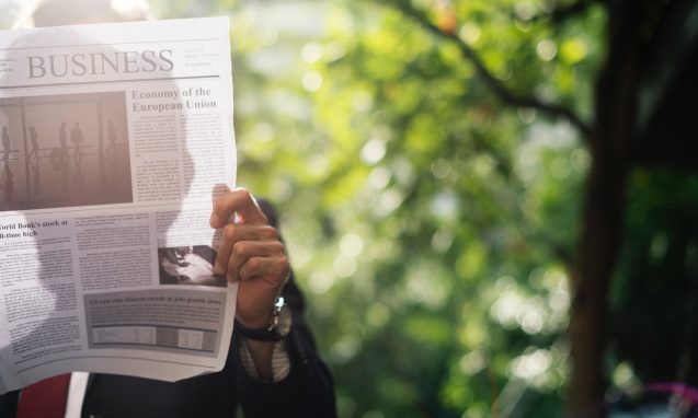 person reads business section of a newspaper