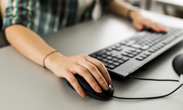 woman using a keyboard and mouse to access her computer