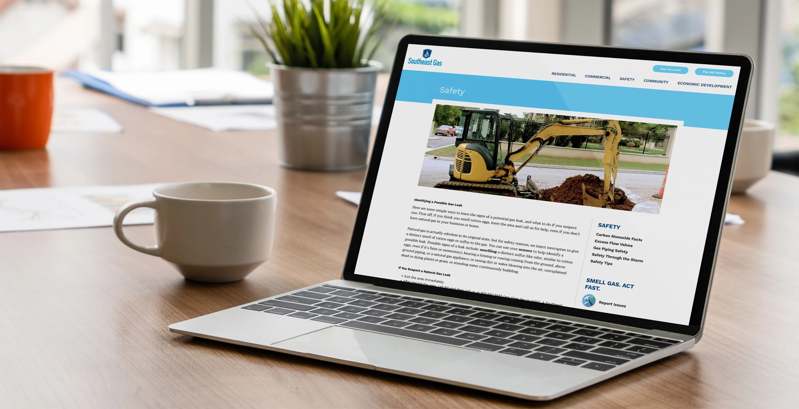 A laptop on a wooden table with a coffee mug next to it