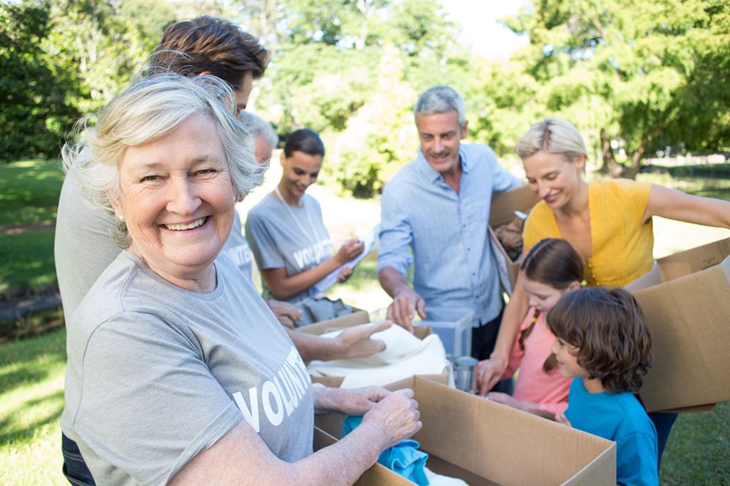 A diverse group of neighbors old and young happily donating clothes to charity on a sunny afternoon outside