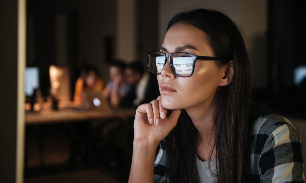 woman wearing glasses looking at a computer screen